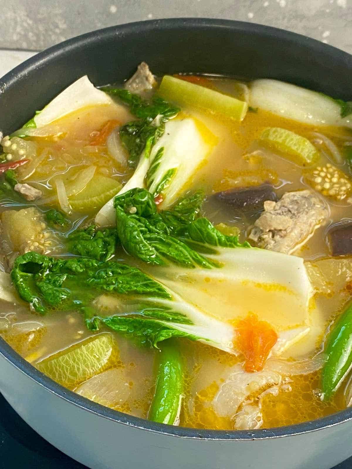 a pot of sinigang na manok with chillies