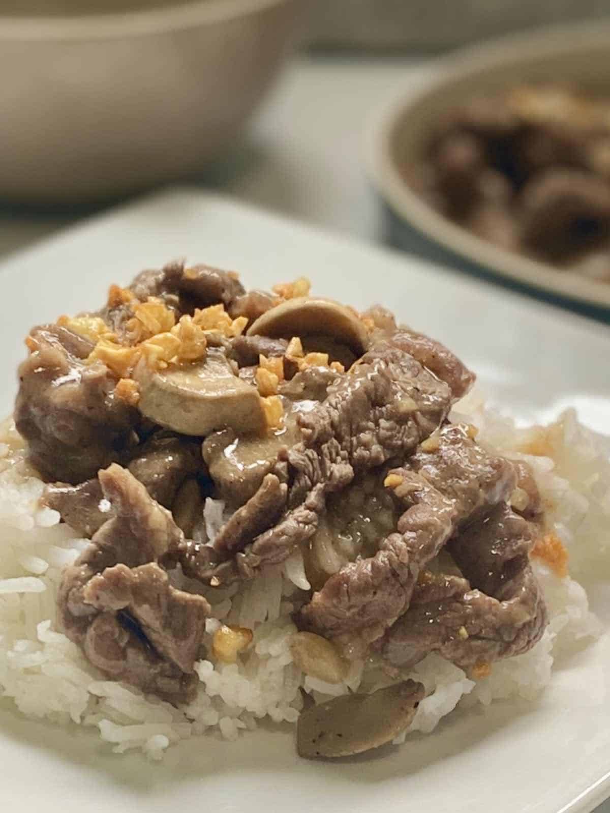 garlic pepper beef served over steamed rice in a white plate