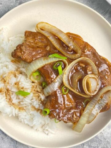 pork bisket served with rice topped with onion slices