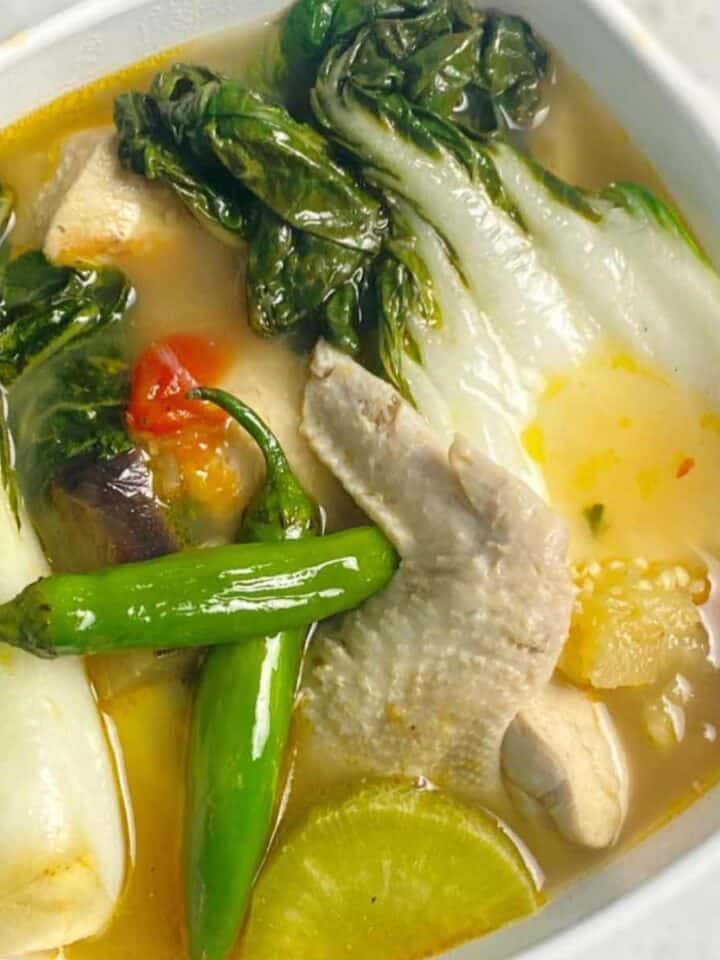 sinigang na manok in a white bowl with chicken wing piece.