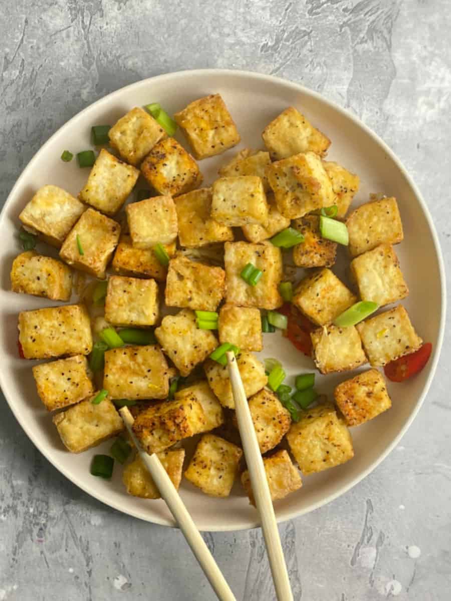 a plate of salt and pepper tofu top with green onions and red chili