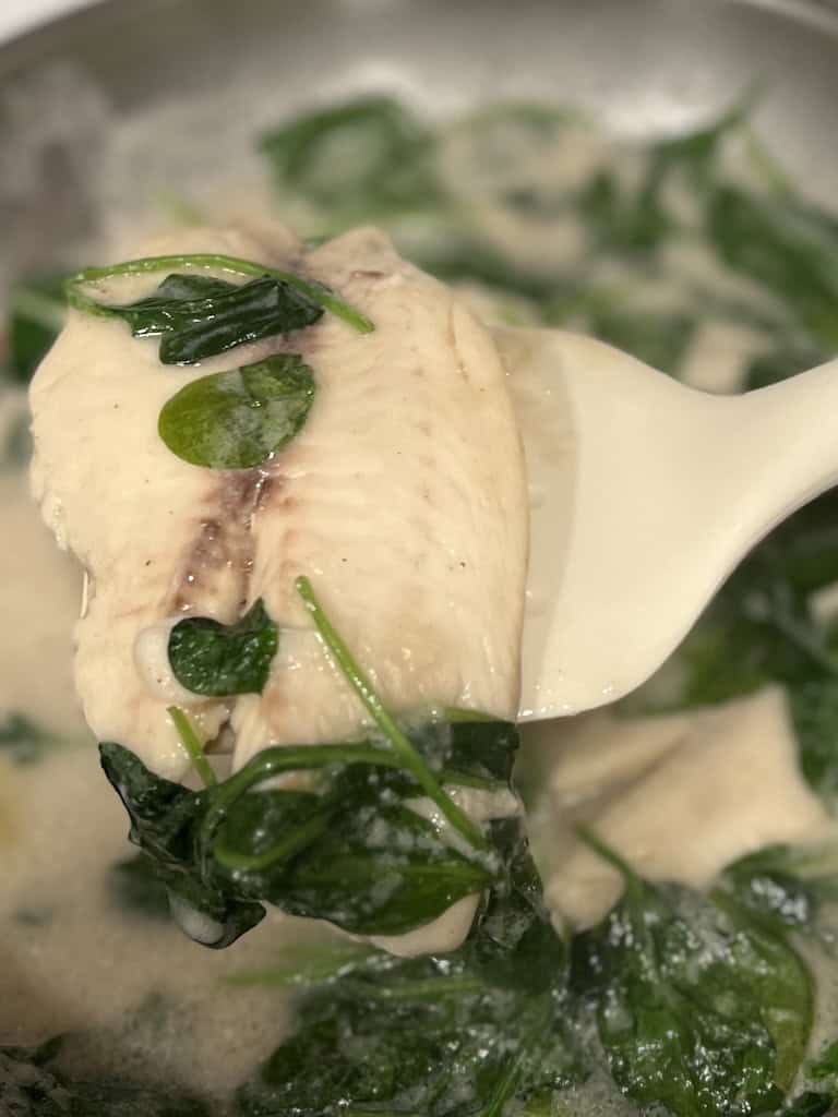 ginataang tilapia in a pan with spinach