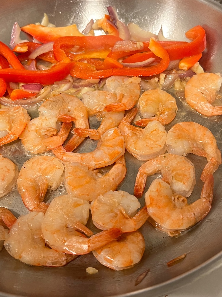 Sautéed shrimp with onions, garlic, and other aromatics in a pan